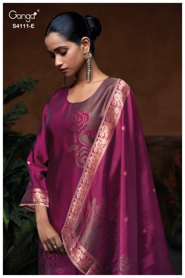 Woman wearing a purple saree with gold embroidery against a dark background