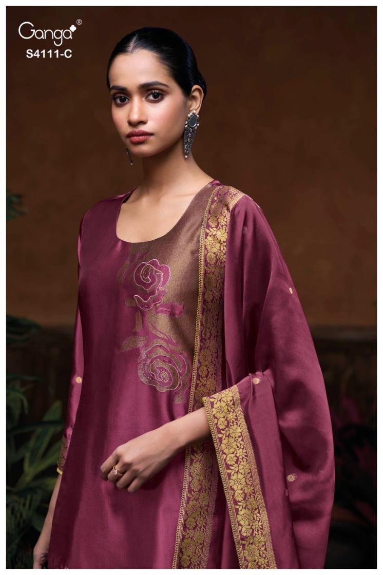 Woman wearing a maroon traditional outfit with gold embroidery against a dark background