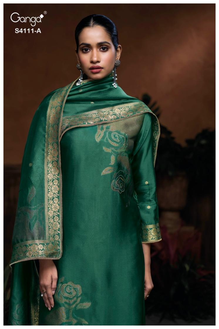 Woman wearing a green traditional outfit with intricate patterns, standing against a dark background.